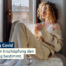 Erschöpfte Person mit Tasse am Fenster, mit Decke: Alltag mit Long COVID und ME/CFS